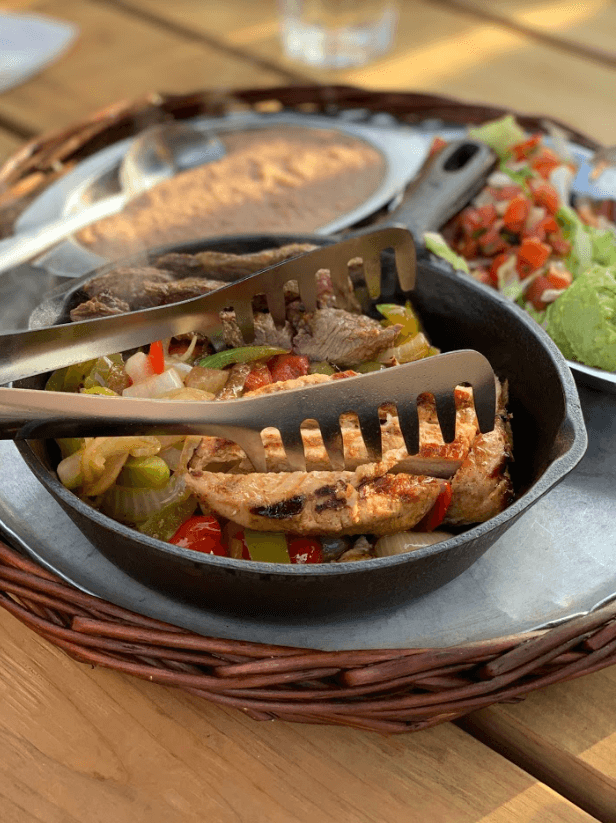 chicken and beef fajitas in an iron skillet